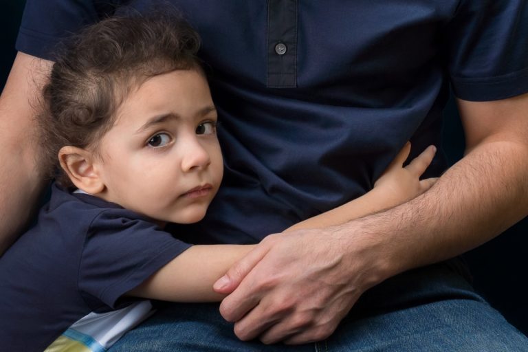 A little boy hugs his father's hand